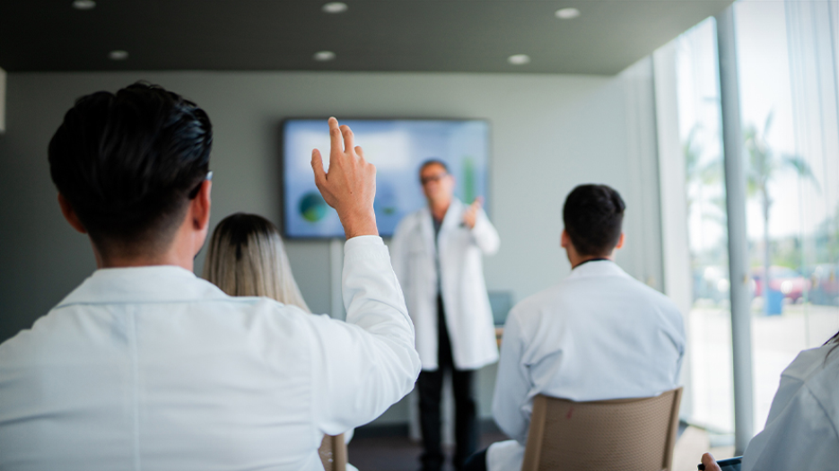 Male clinician raising his hand during a training session.